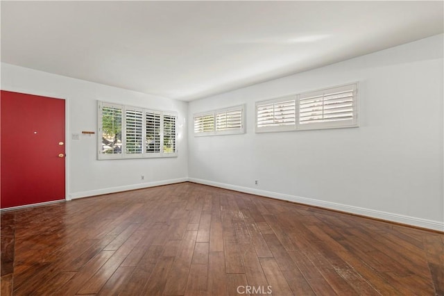 spare room featuring hardwood / wood-style flooring and baseboards