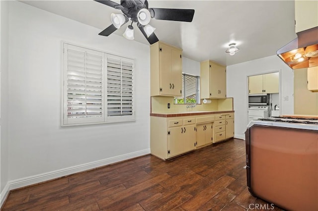 kitchen with stainless steel microwave, cream cabinetry, dark wood-style flooring, and light countertops