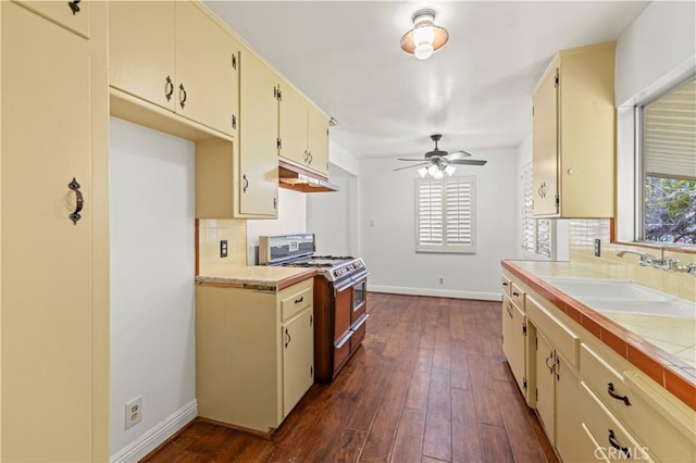 kitchen featuring a wealth of natural light, a sink, cream cabinets, and range with two ovens