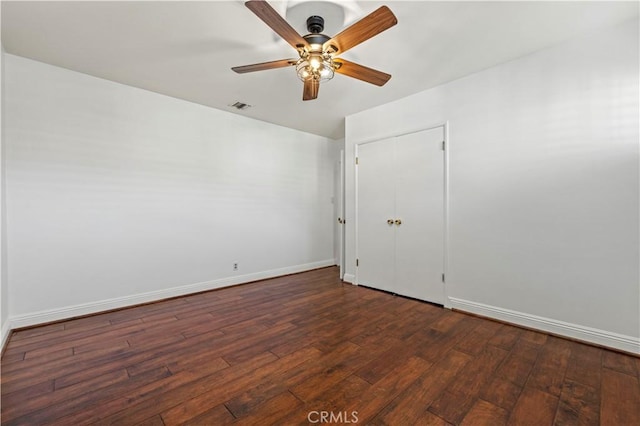 spare room with dark wood-type flooring, baseboards, visible vents, and ceiling fan