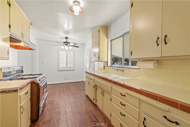 kitchen with tasteful backsplash, under cabinet range hood, double oven range, a wealth of natural light, and cream cabinetry