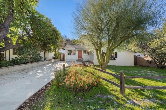 ranch-style house featuring stucco siding, a front lawn, and fence