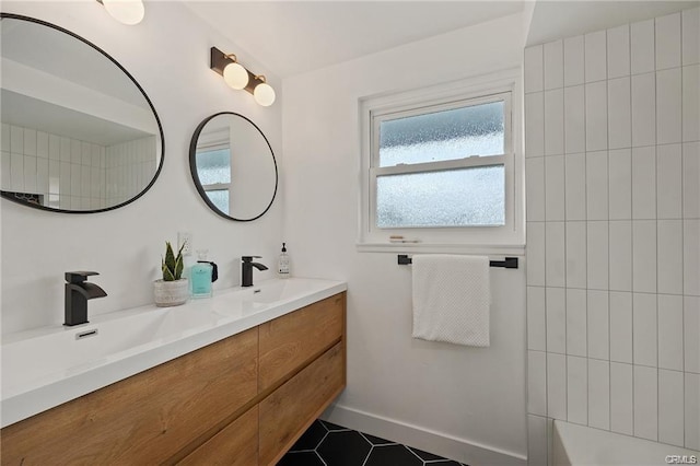 full bath featuring tile patterned flooring, double vanity, baseboards, and a sink