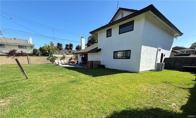 back of property featuring fence, a lawn, and stucco siding