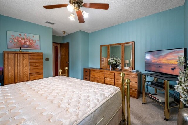 bedroom with ceiling fan, visible vents, carpet floors, and a textured ceiling