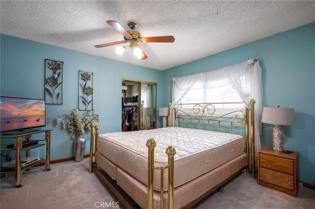 carpeted bedroom with a closet, a textured ceiling, baseboards, and a ceiling fan