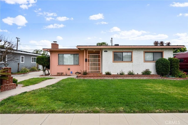 single story home featuring stucco siding, a chimney, and a front yard