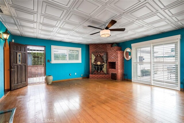 unfurnished living room with an ornate ceiling, a fireplace, a ceiling fan, and wood finished floors