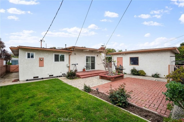 back of house with fence, a yard, stucco siding, a deck, and a patio area