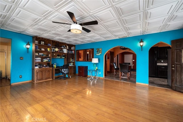 interior space featuring an ornate ceiling, arched walkways, and wood finished floors