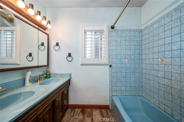 bathroom with tub / shower combination, wood finished floors, baseboards, and a sink