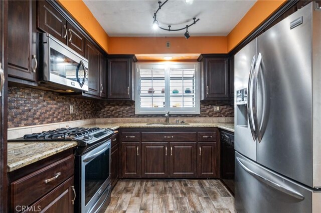 kitchen featuring a sink, decorative backsplash, stainless steel appliances, dark brown cabinets, and light wood-style floors