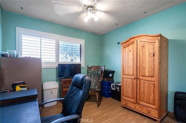 office space featuring a textured ceiling, ceiling fan, and light wood finished floors