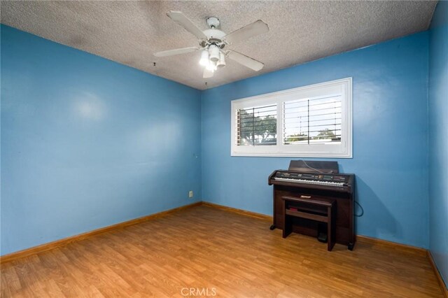 spare room with baseboards, a textured ceiling, a ceiling fan, and wood finished floors