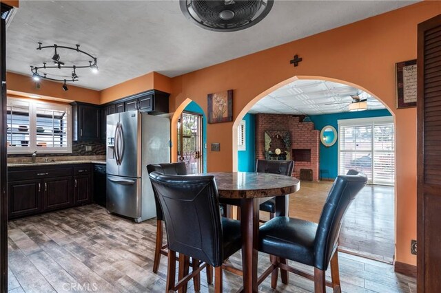 dining room featuring arched walkways, a fireplace, a wealth of natural light, and wood finished floors