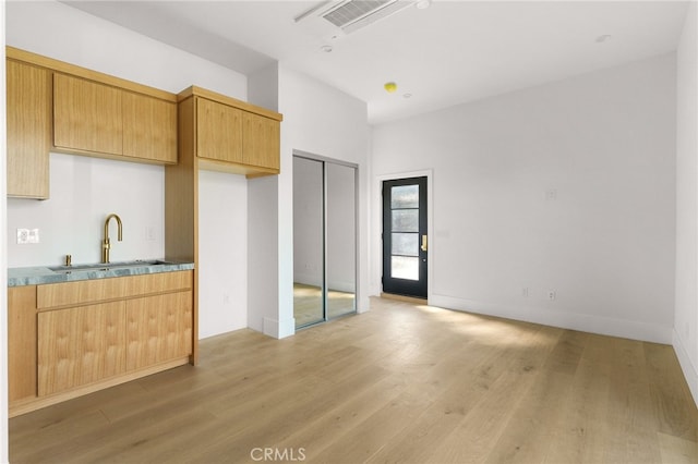 kitchen with visible vents, light wood finished floors, and a sink