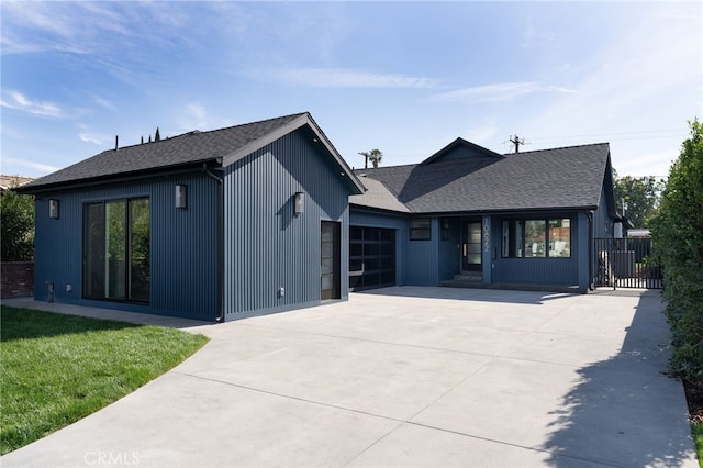 modern farmhouse with a front lawn, concrete driveway, an attached garage, and a shingled roof