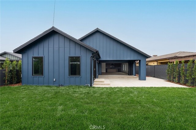 back of house with a patio, a yard, fence, and board and batten siding