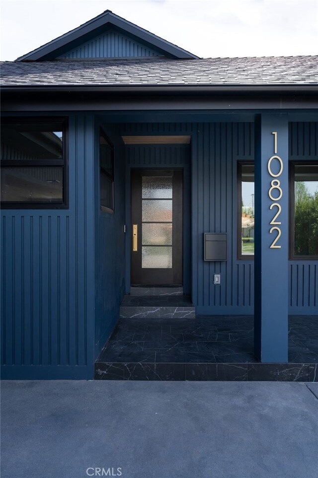 entrance to property featuring roof with shingles