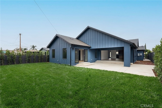 rear view of house featuring a lawn, board and batten siding, roof with shingles, and fence