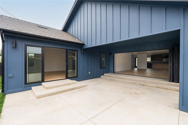 rear view of property with a patio area, board and batten siding, and driveway