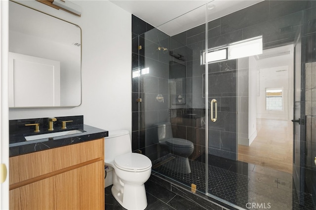 bathroom with tile patterned floors, a shower stall, toilet, and vanity