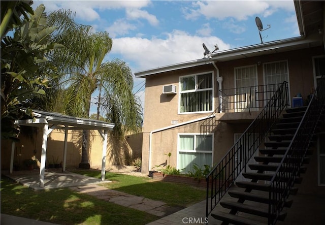 back of house featuring a patio, a wall unit AC, fence, stucco siding, and stairs