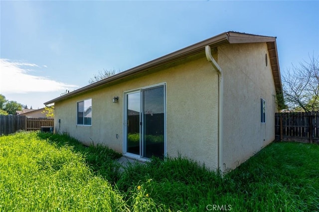 rear view of property with stucco siding and fence