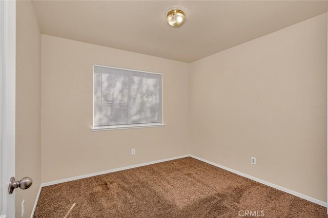 empty room featuring carpet flooring and baseboards