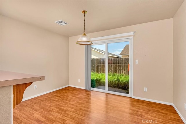 unfurnished dining area with visible vents, baseboards, and wood finished floors