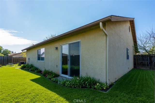 back of property featuring a yard, central air condition unit, stucco siding, and fence