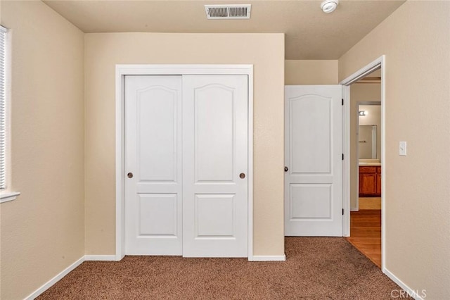 unfurnished bedroom with visible vents, baseboards, a closet, and carpet flooring