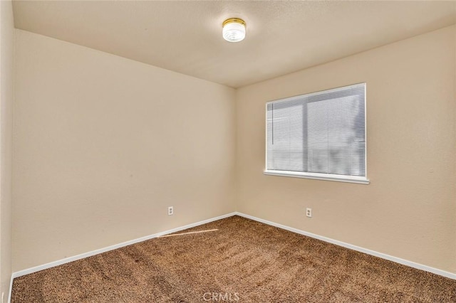 carpeted spare room featuring baseboards