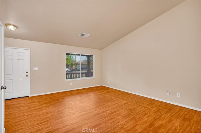 spare room with visible vents, light wood-style flooring, lofted ceiling, and baseboards