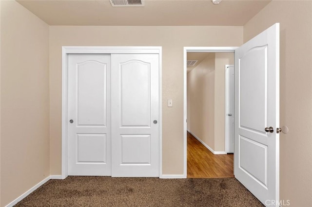 unfurnished bedroom with visible vents, carpet flooring, baseboards, and a closet