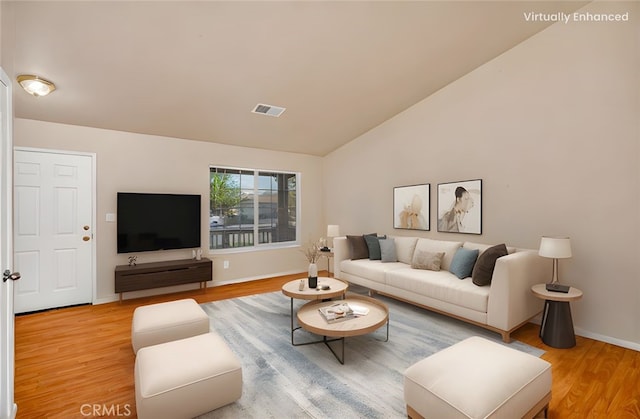 living area featuring vaulted ceiling, light wood-style floors, baseboards, and visible vents