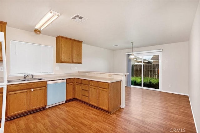 kitchen featuring visible vents, a peninsula, white dishwasher, a sink, and light countertops