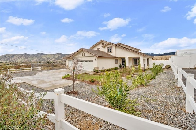 view of property exterior with an attached garage, fence private yard, concrete driveway, stucco siding, and a mountain view