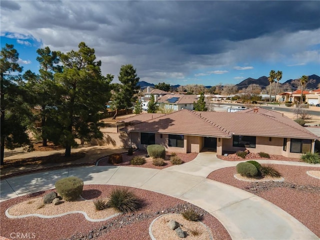 ranch-style house with a tile roof, stucco siding, concrete driveway, and a residential view