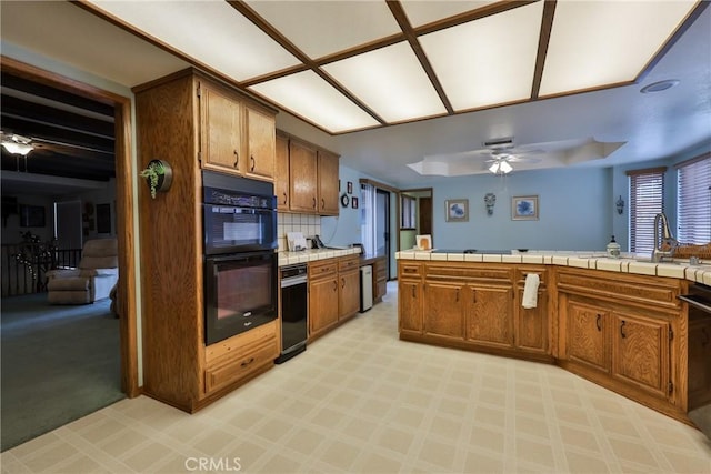 kitchen with black appliances, tile countertops, brown cabinetry, and ceiling fan