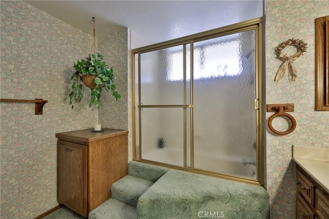 full bath with enclosed tub / shower combo, wallpapered walls, and vanity