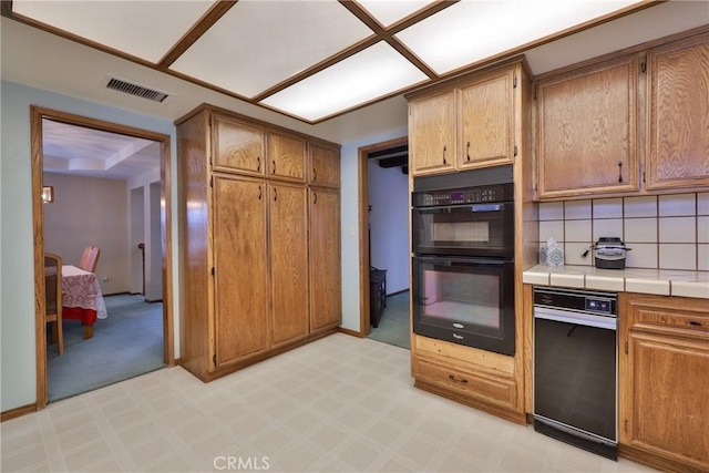 kitchen with tile countertops, visible vents, dobule oven black, tasteful backsplash, and brown cabinets