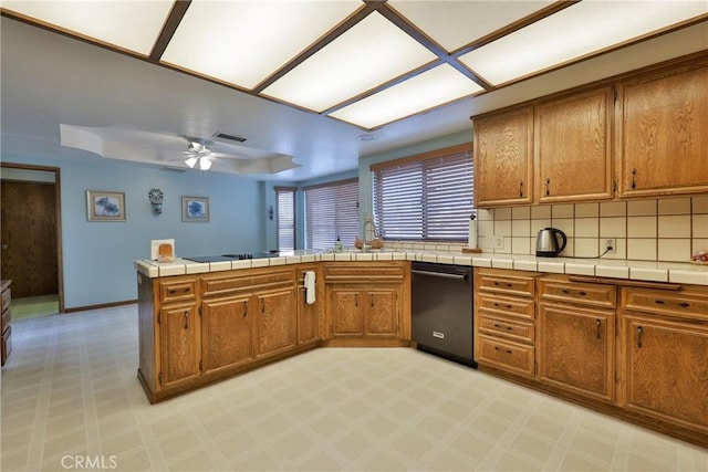 kitchen with black appliances, a peninsula, brown cabinets, and a sink