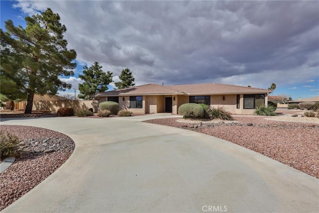 ranch-style house featuring stucco siding and driveway