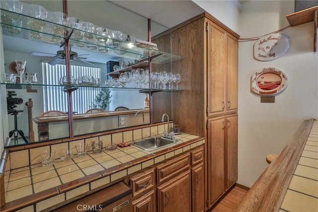 bar featuring wet bar, ceiling fan, and a sink