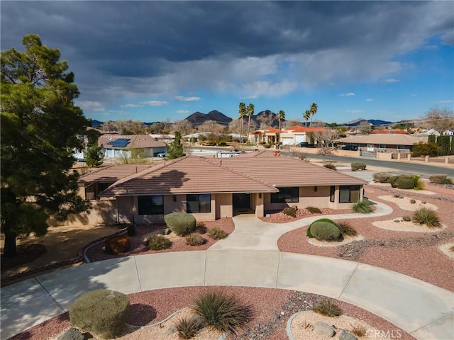 ranch-style house featuring a mountain view, stucco siding, driveway, and a tiled roof