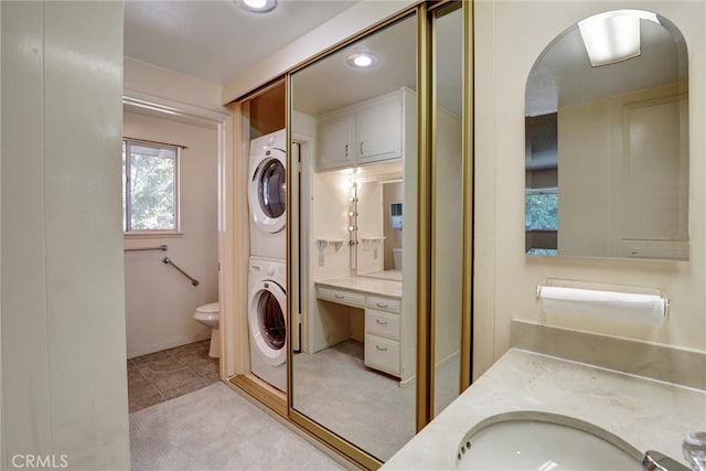 full bathroom with toilet, stacked washer and clothes dryer, vanity, and tile patterned flooring