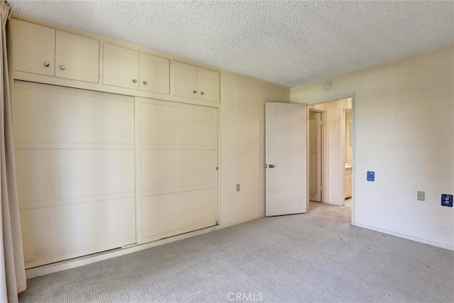 unfurnished bedroom featuring a closet, a textured ceiling, and light colored carpet