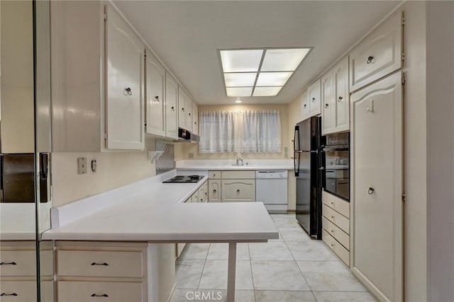 kitchen featuring black appliances, light tile patterned floors, light countertops, a peninsula, and under cabinet range hood
