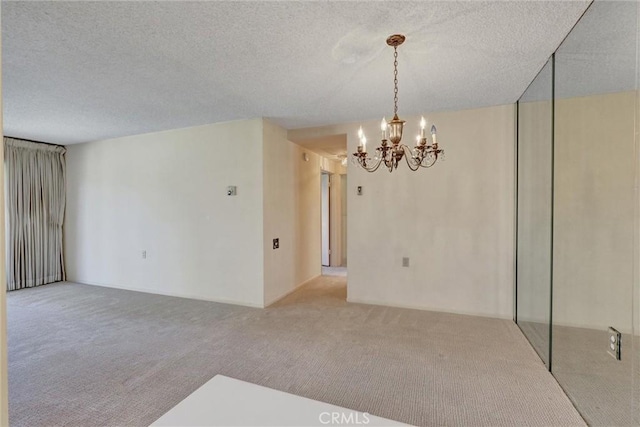 unfurnished room featuring a notable chandelier, carpet flooring, and a textured ceiling